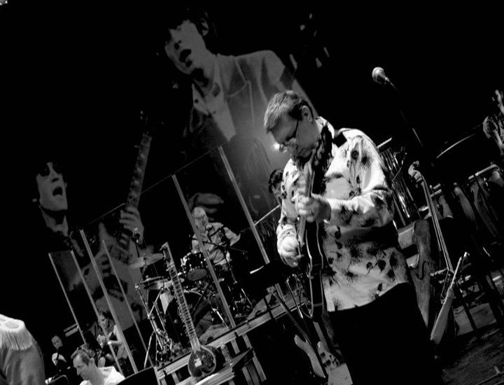 Elliot Reed playing guitar on stage at Beatles tribute concert